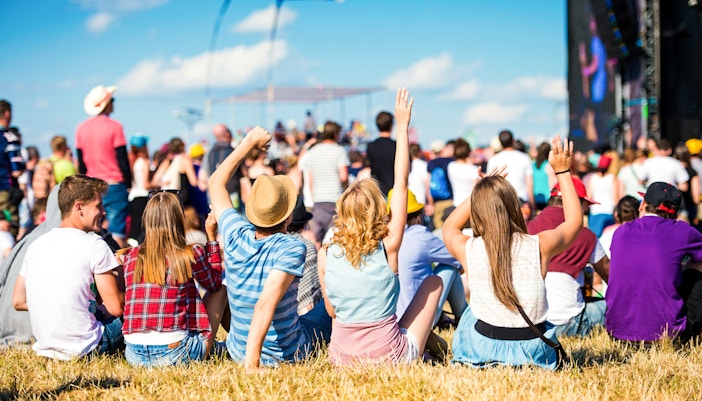Crowd enjoying a summer festival with live music and colorful kites.