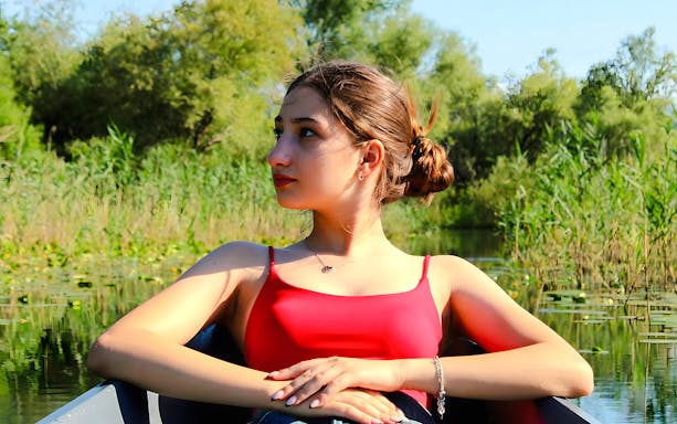 Woman relaxing on a boat during Lake Skadar tour, surrounded by lush greenery.
