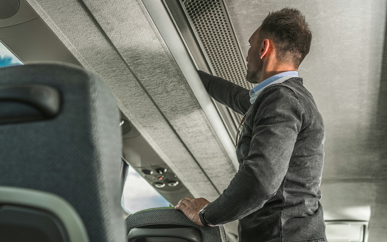 Passenger using overhead luggage storage on Hong Kong Airport Express.