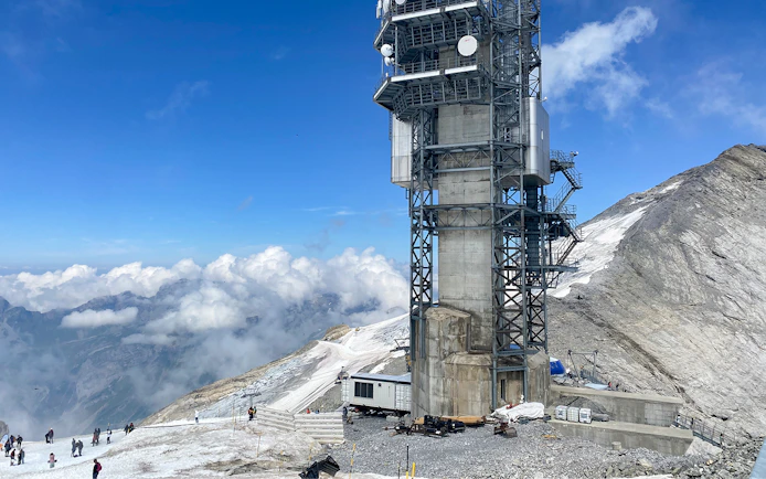 Towering structure on Mt. Titlis with snowy landscape and tourists, Engelberg tour from Lucerne.