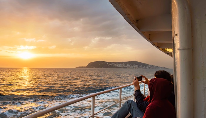 Bosphorus yacht cruising at sunset with Istanbul skyline in the background.