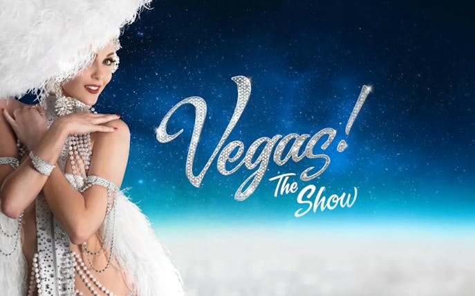 Showgirl in feathered costume with "Vegas! The Show" text on starry background.