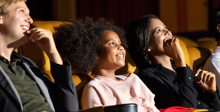 Family enjoying a movie in a theater, smiling and relaxed.