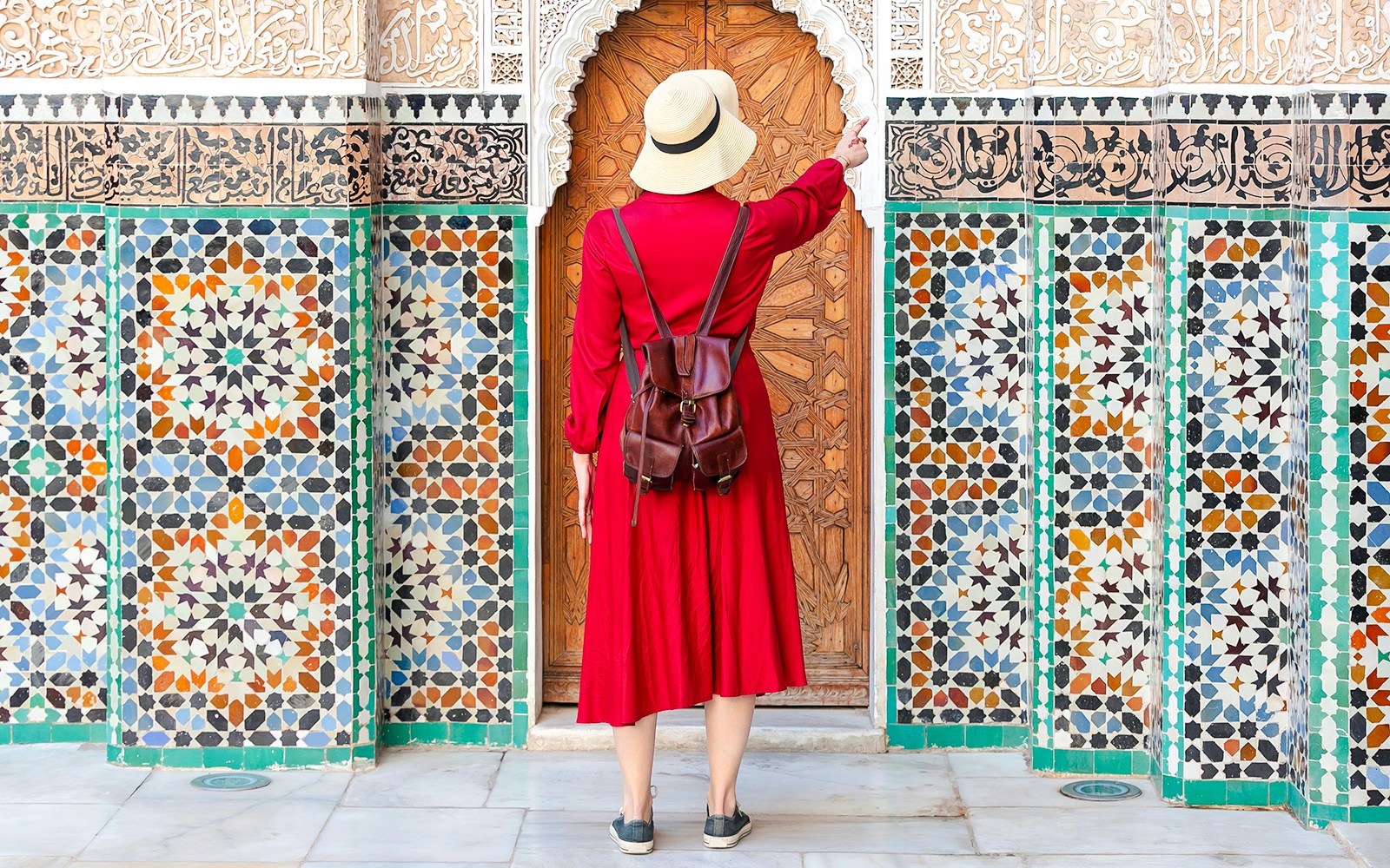 Woman admiring intricate tiles at Ben Youssef Madrasa, Marrakesh, Morocco.