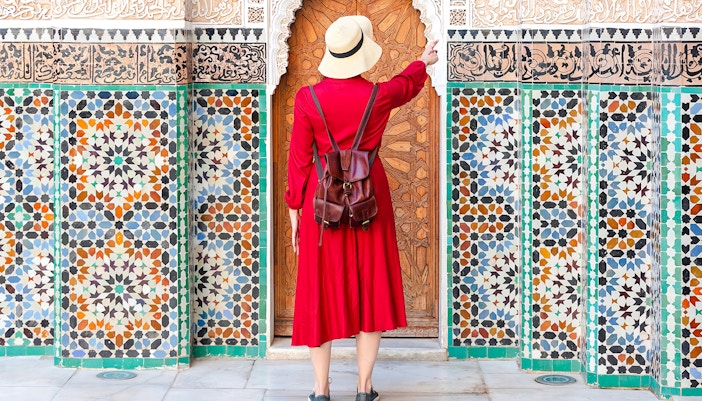 Woman admiring intricate tiles at Ben Youssef Madrasa, Marrakesh, Morocco.