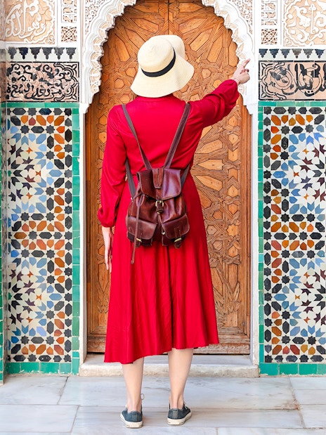 Woman admiring intricate tiles at Ben Youssef Madrasa, Marrakesh, Morocco.