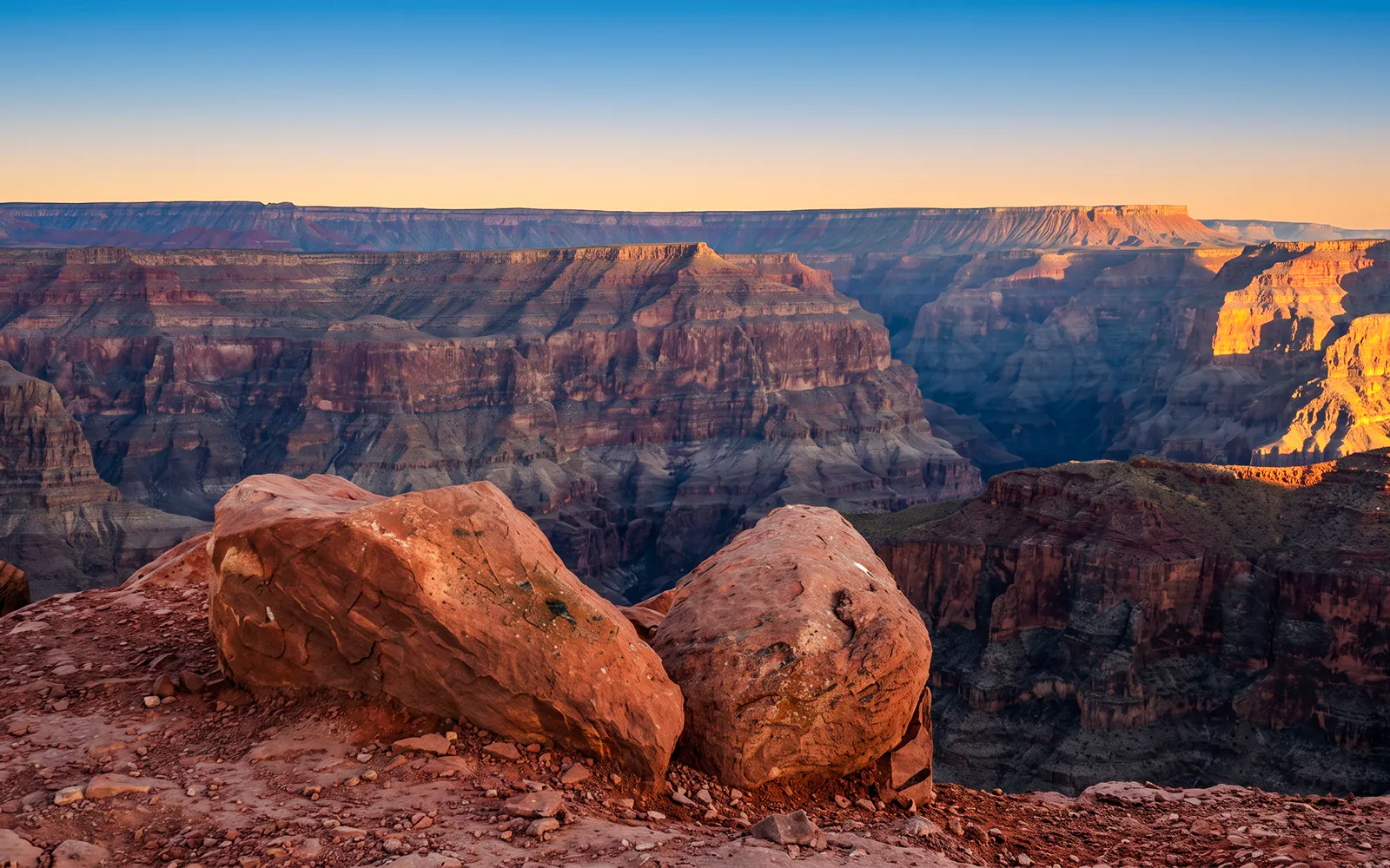 Grand Canyon West at sunset with rocky foreground and layered canyon views.