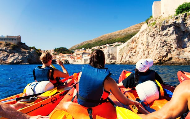 Kayakers paddling between rocky cliffs on the Adriatic Sea near Dubrovnik.