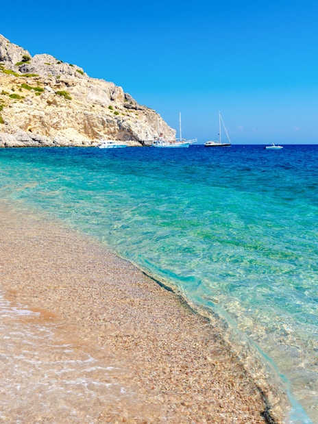 Afandou Beach shoreline with clear blue water and boats, Rhodes island, Greece.