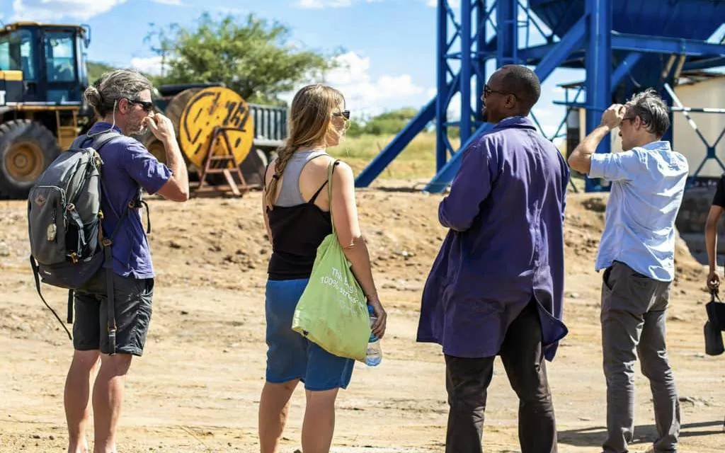 Tourists exploring Mererani Tanzanite Mine with guide, machinery in background, Arusha or Moshi.