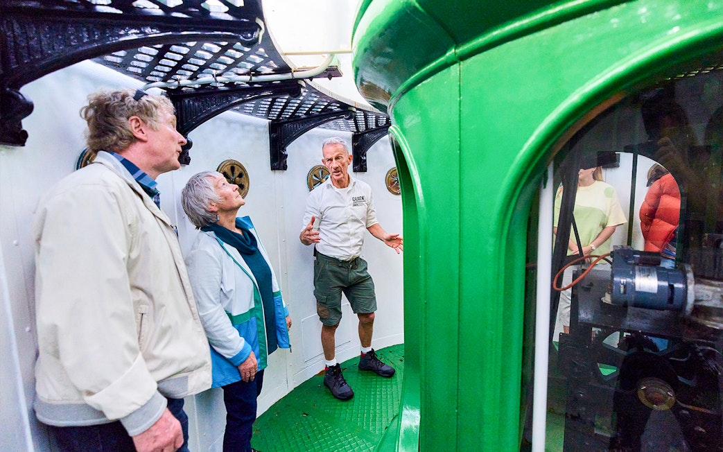 Tour guide explaining inside Cape Leeuwin Lighthouse lamp room to visitors.