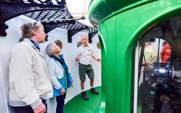 Tour guide explaining inside Cape Leeuwin Lighthouse lamp room to visitors.