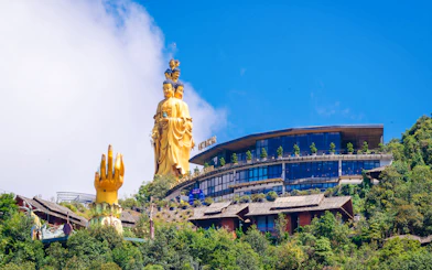 Golden Buddha statue and hand sculpture at O Quy Ho Heaven Gate, Sa Pa, with surrounding greenery.