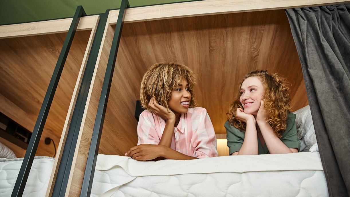 Two people relaxing in a bunk bed at Homestay Cave Hostel.