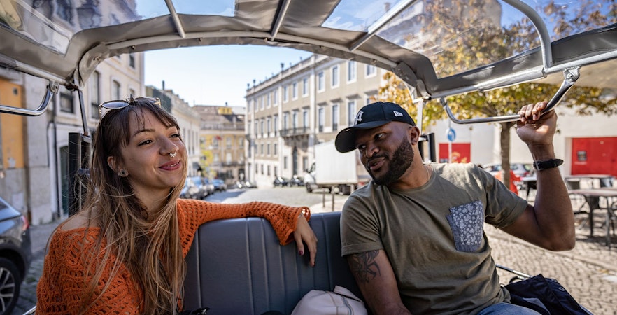 Tourists enjoying a tuk tuk ride through Lisbon streets.