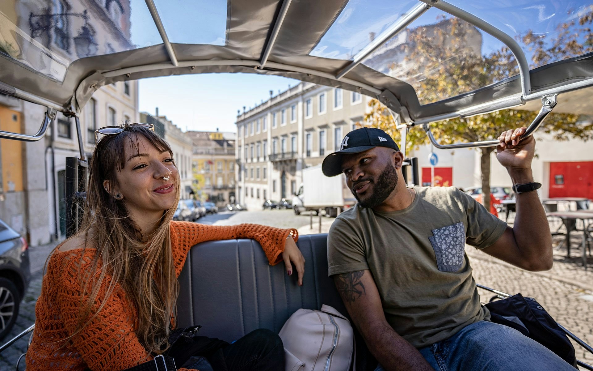 Tourists enjoying a tuk tuk ride through Lisbon streets.