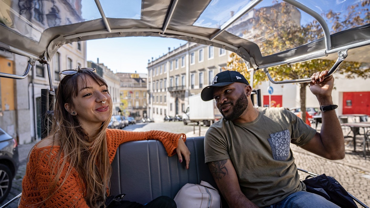 Tourists enjoying a tuk tuk ride through Lisbon streets.