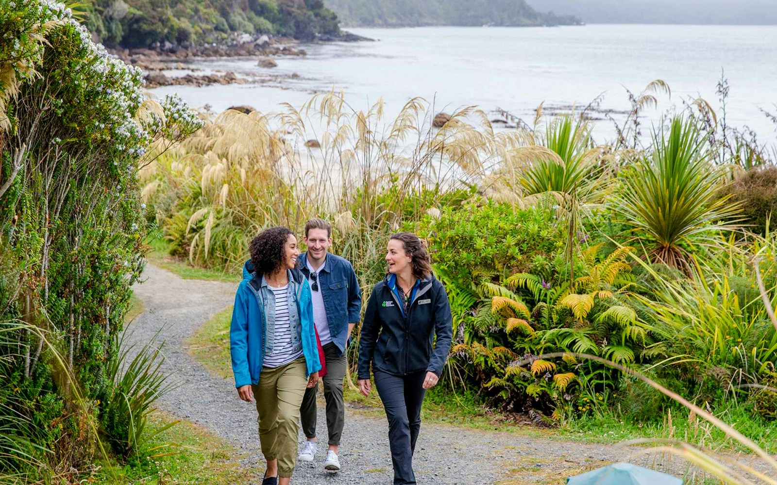 Group walking on a coastal path surrounded by lush greenery on Stewart Island tour.