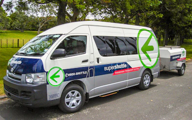 Super Shuttle van parked in a green area, used for airport transfers.