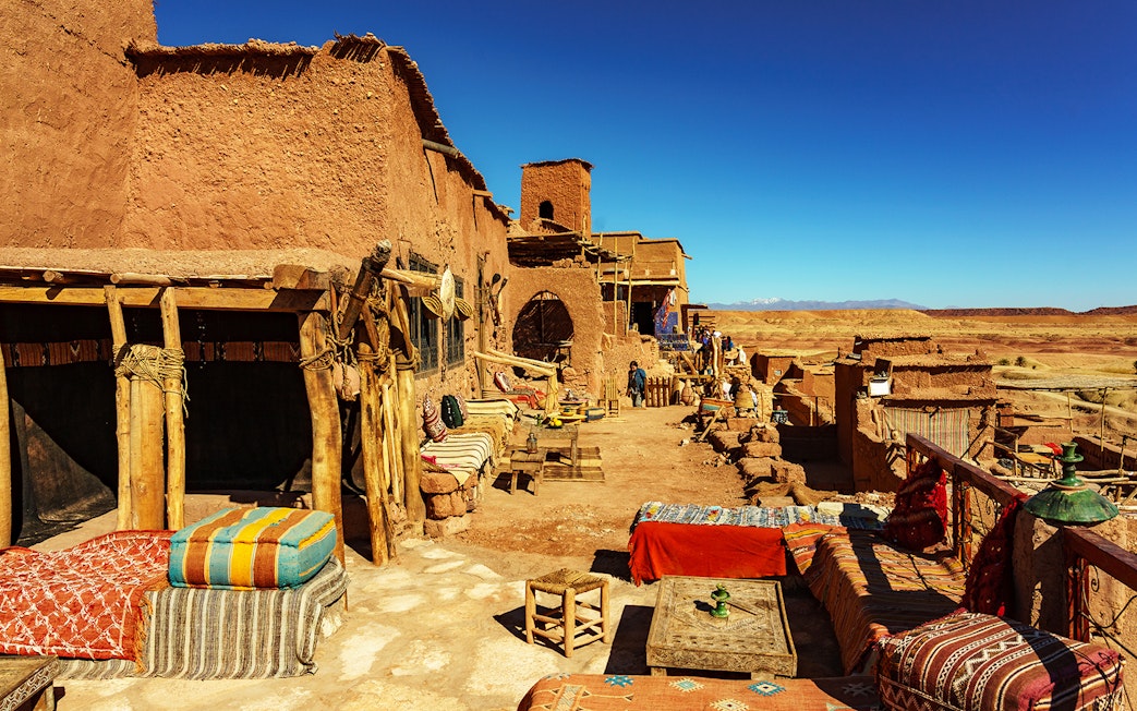 Tourists exploring Ait Benhaddou Kasbah's historic architecture on a day trip from Marrakech, Morocco.