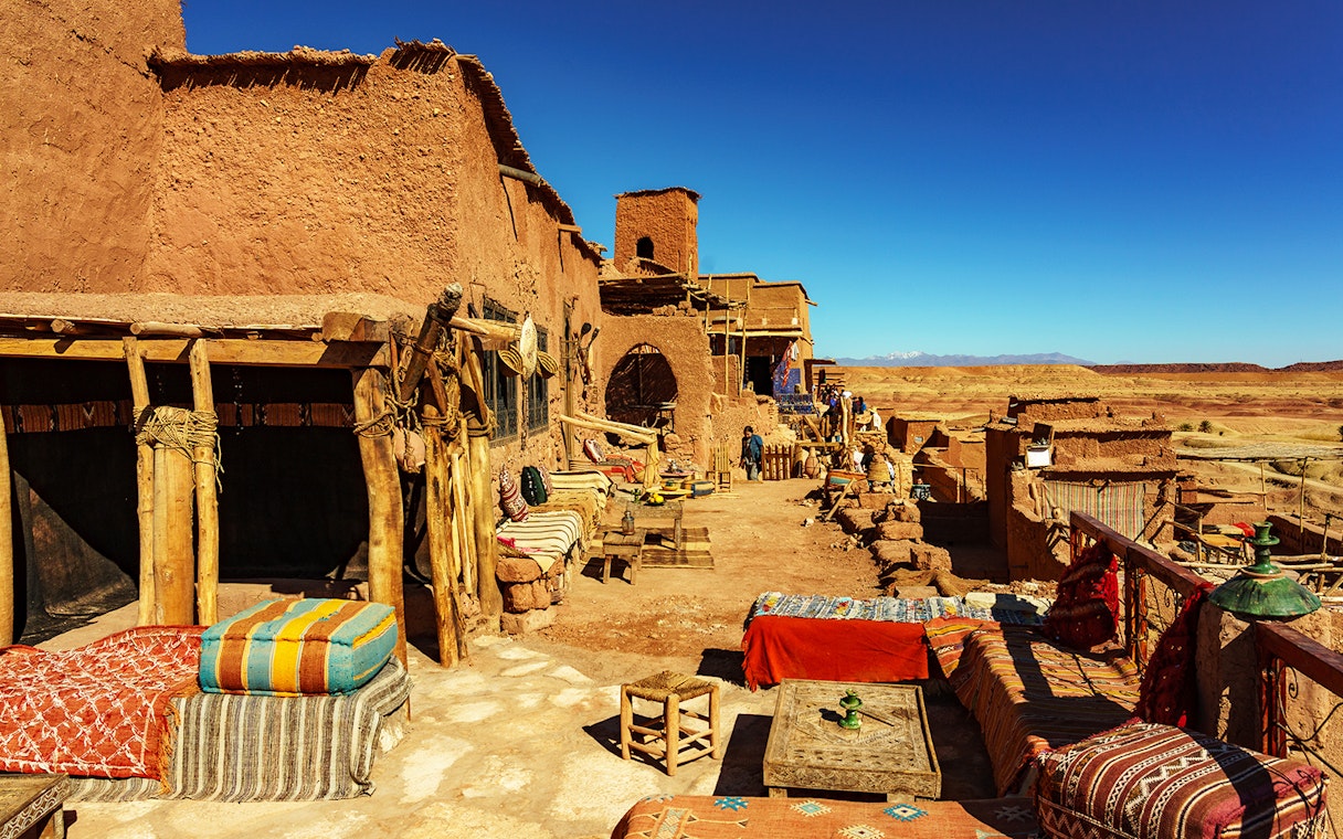 Tourists exploring Ait Benhaddou Kasbah's historic architecture on a day trip from Marrakech, Morocco.