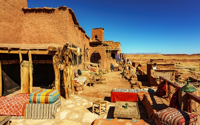 Tourists exploring Ait Benhaddou Kasbah's historic architecture on a day trip from Marrakech, Morocco.