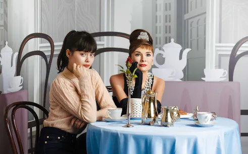 Two women sitting at a table with tea set at Madame Tussauds Tokyo.
