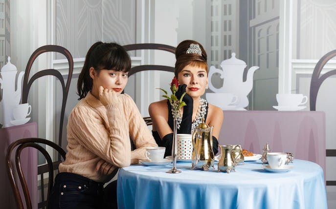 Two women sitting at a table with tea set at Madame Tussauds Tokyo.