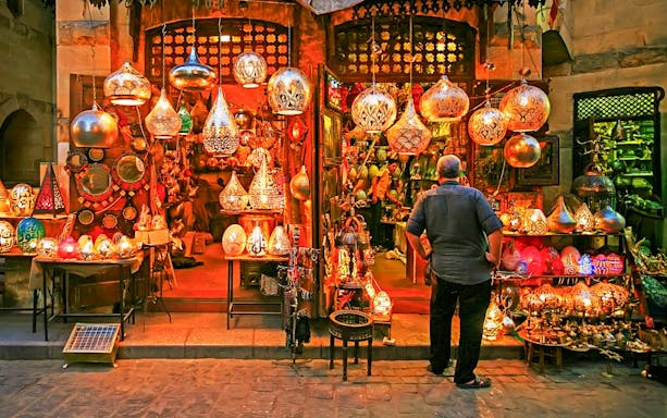 Bazaar in Cairo with colorful lanterns and a man browsing, part of Citadel and Egyptian Museum tour.