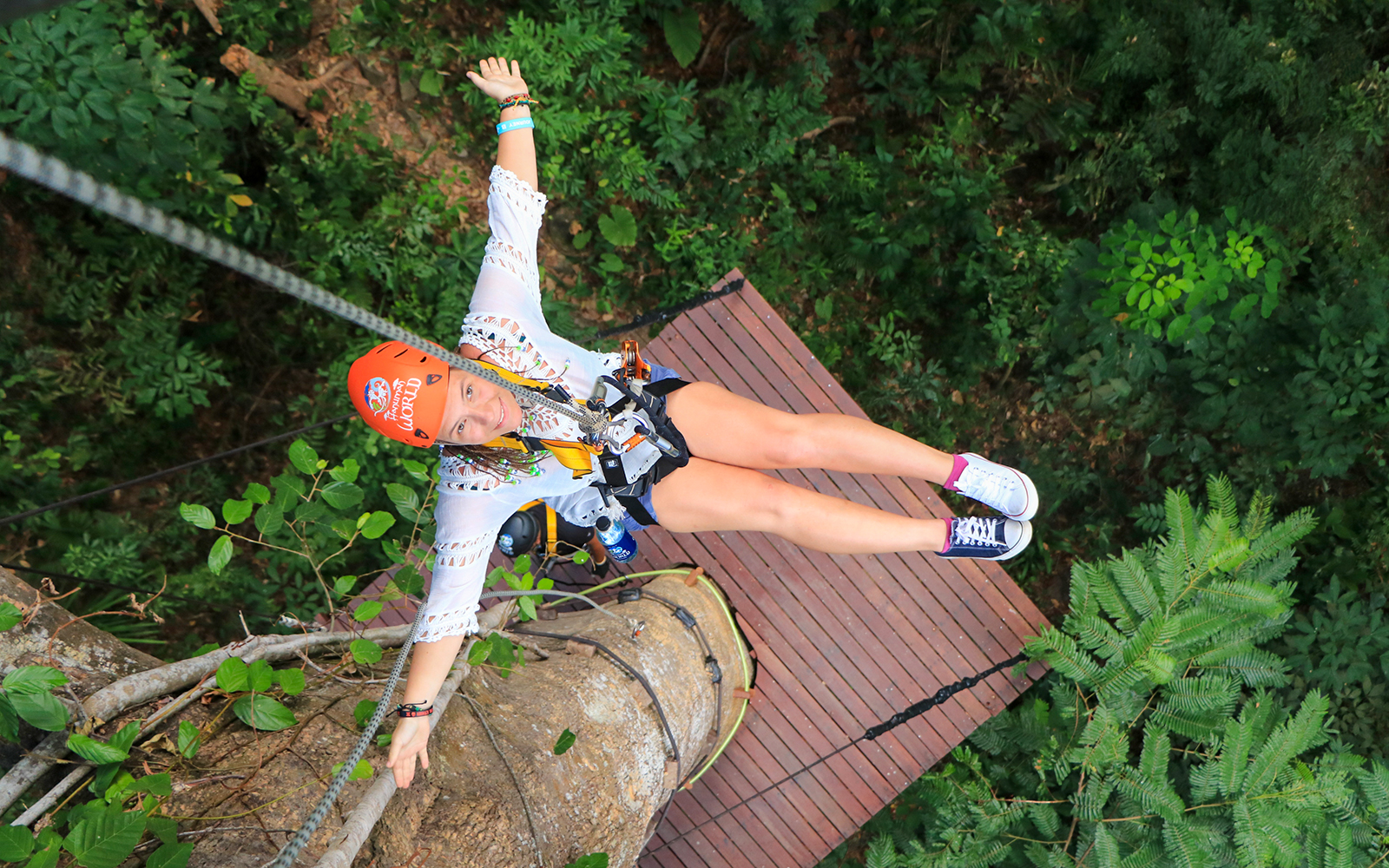 Woman ziplining at Hanuman World, Phuket, Thailand, surrounded by lush greenery.