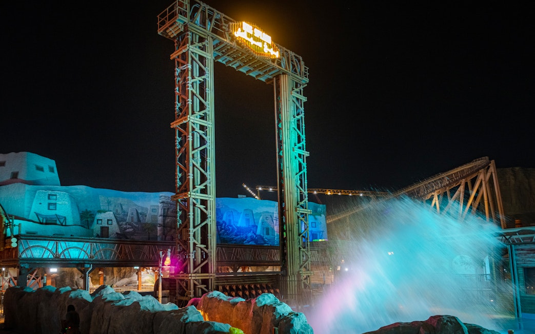 Water ride splash at night in Six Flags Qiddiya City, with illuminated structures in the background.