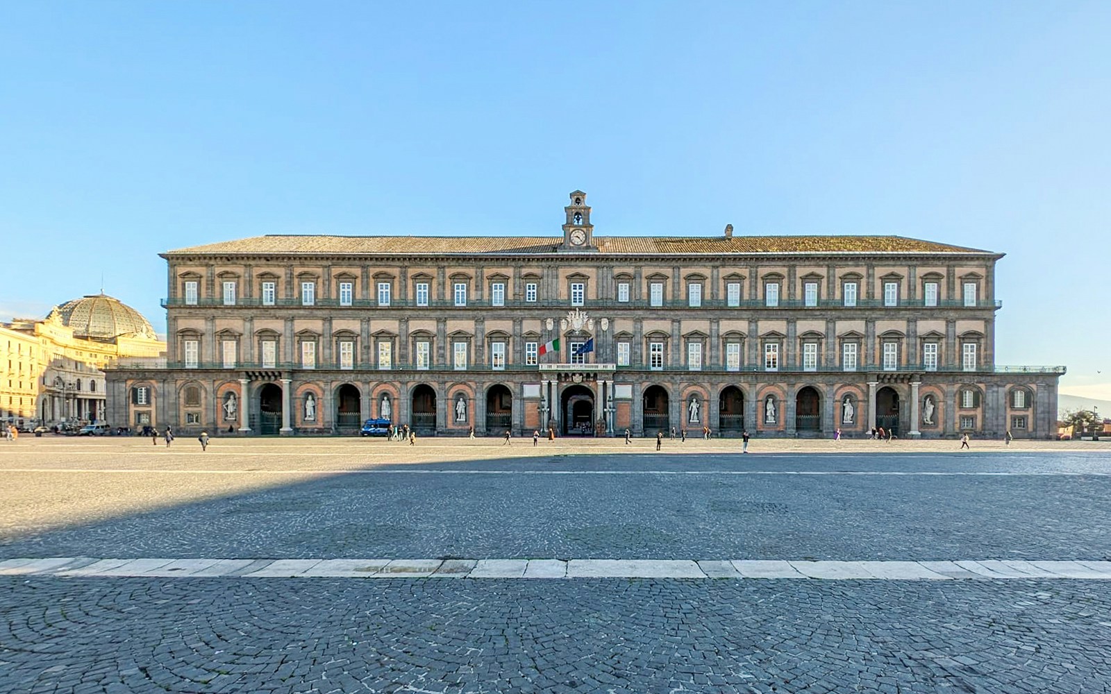 Palazzo Reale in Naples with tourists exploring the historic architecture.