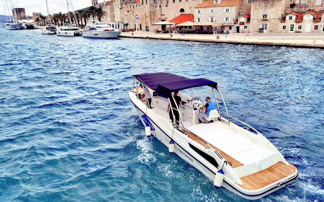 Boat cruising near historic waterfront on 5 Islands Hopping Tour with Blue Cave visit.