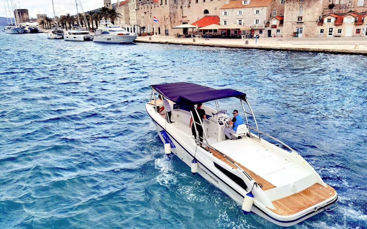 Boat cruising near historic waterfront on 5 Islands Hopping Tour with Blue Cave visit.