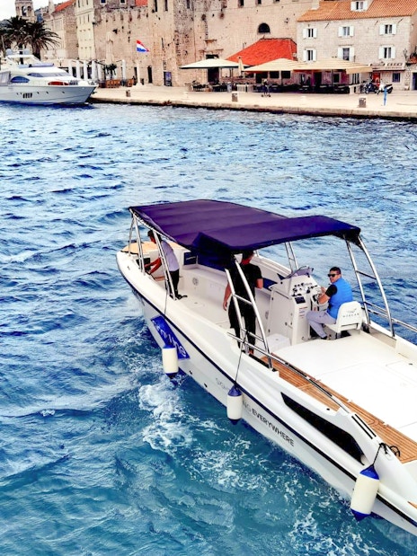 Boat cruising near historic waterfront on 5 Islands Hopping Tour with Blue Cave visit.