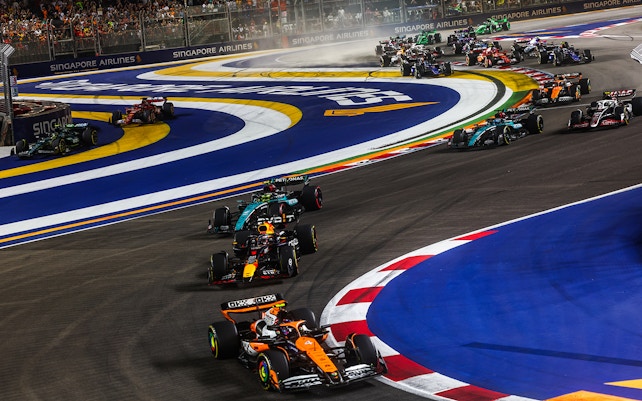 F1 cars racing at night on the Marina Bay Street Circuit, Singapore.