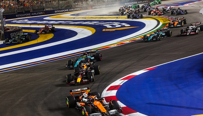F1 cars racing at night on the Marina Bay Street Circuit, Singapore.