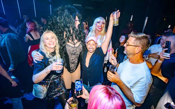 Group enjoying nightlife at a West End club, featuring drag performers and lively crowd.