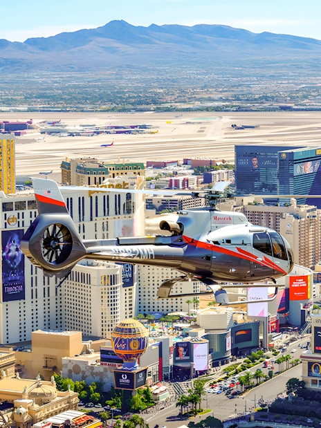 Maverick Helicopter flying over the Las Vegas Strip with cityscape view.