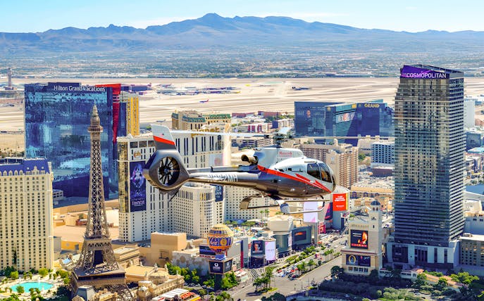 Maverick Helicopter flying over the Las Vegas Strip with cityscape view.