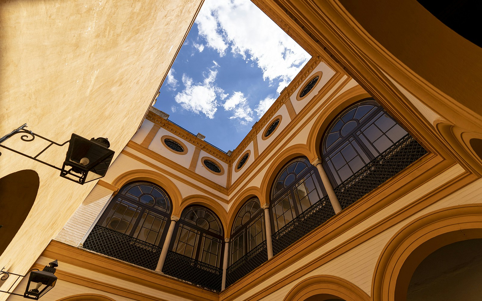 House of Trade courtyard in Alcazar Seville with intricate arches and lush gardens.