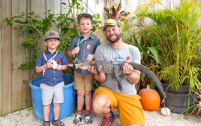 Guests holding a small alligator at Everglades Holiday Park animal encounter.