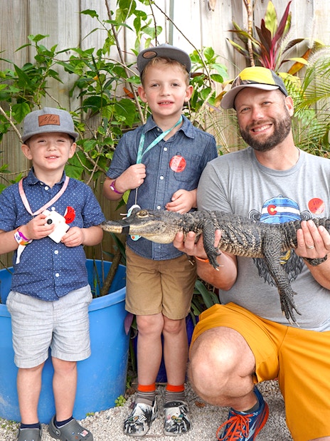 Guests holding a small alligator at Everglades Holiday Park animal encounter.