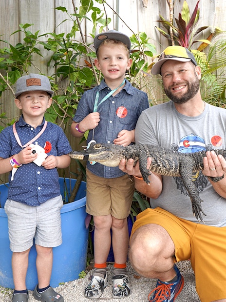 Guests holding a small alligator at Everglades Holiday Park animal encounter.
