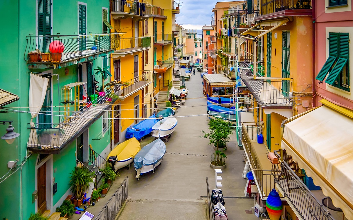 Colorful buildings and boats in a narrow street of Cinque Terre, part of Florence to Cinque Terre tour.