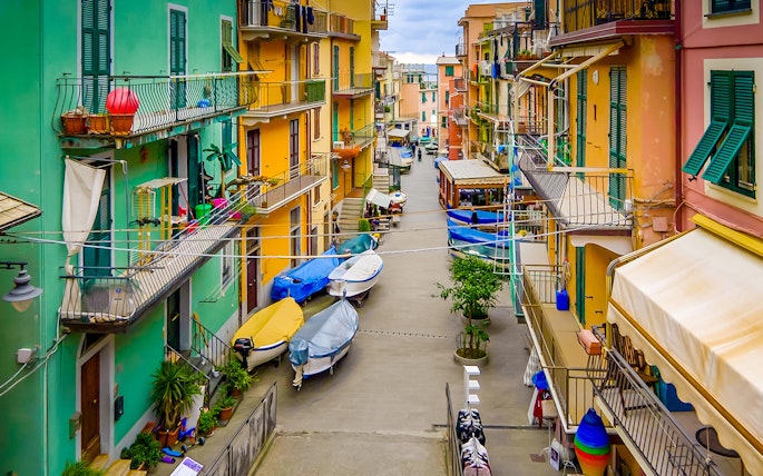 Colorful buildings and boats in a narrow street of Cinque Terre, part of Florence to Cinque Terre tour.
