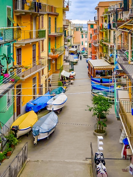 Colorful buildings and boats in a narrow street of Cinque Terre, part of Florence to Cinque Terre tour.