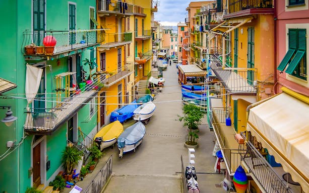 Colorful buildings and boats in a narrow street of Cinque Terre, part of Florence to Cinque Terre tour.