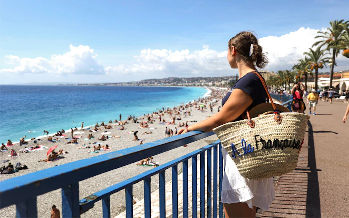 Woman overlooking Promenade des Anglais beach in Nice during walking tour.