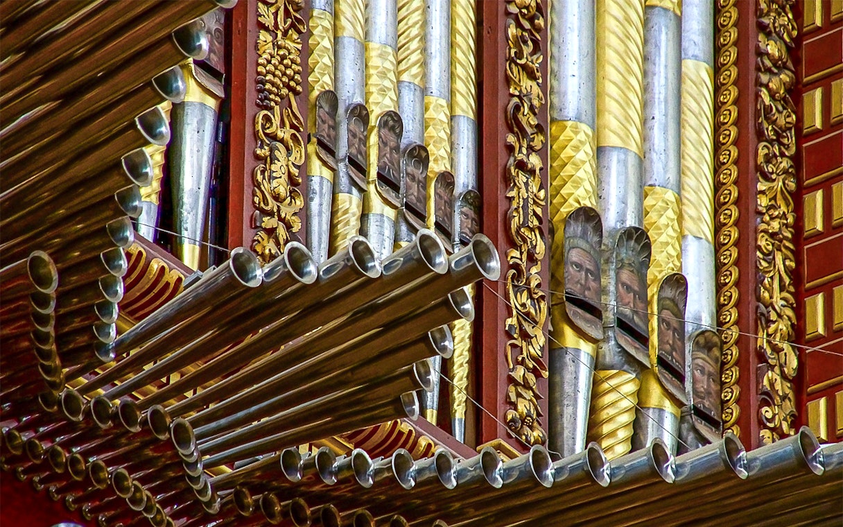 Ornate organ pipes inside Córdoba Cathedral-Mosque, featuring intricate gold and silver designs.